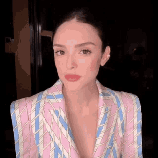 a close up of a woman wearing a pink and blue striped suit .