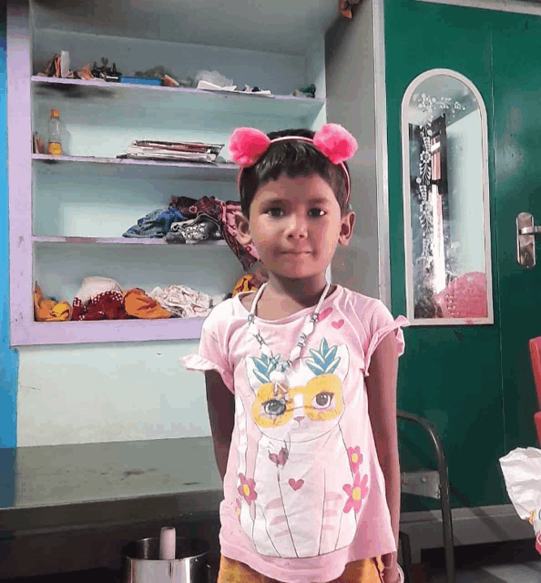 a little girl wearing a pink top with a mask on it