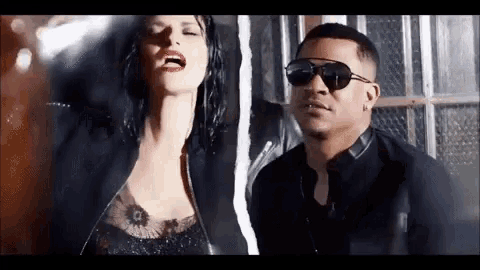 a man and a woman are standing next to each other . the woman is wearing sunglasses .