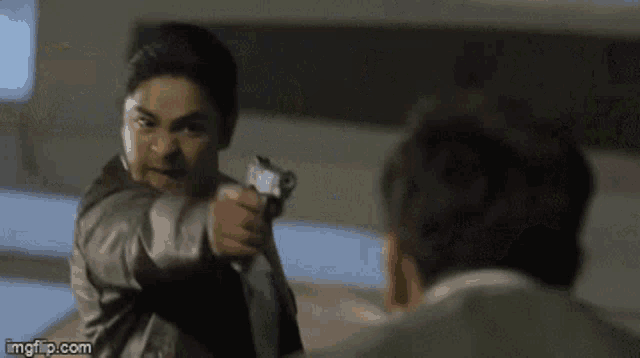 a man is pointing a gun at another man in a movie .