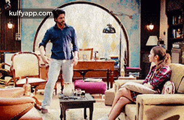 a man is standing in front of a woman sitting on a couch .