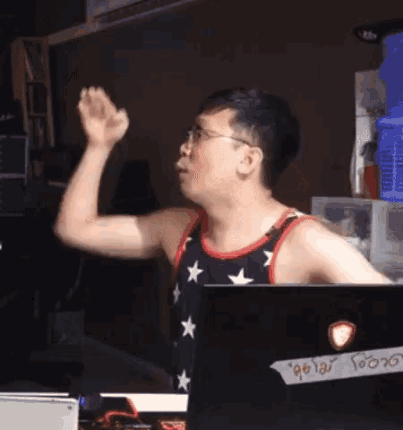 a man wearing an american flag tank top is waving his hand