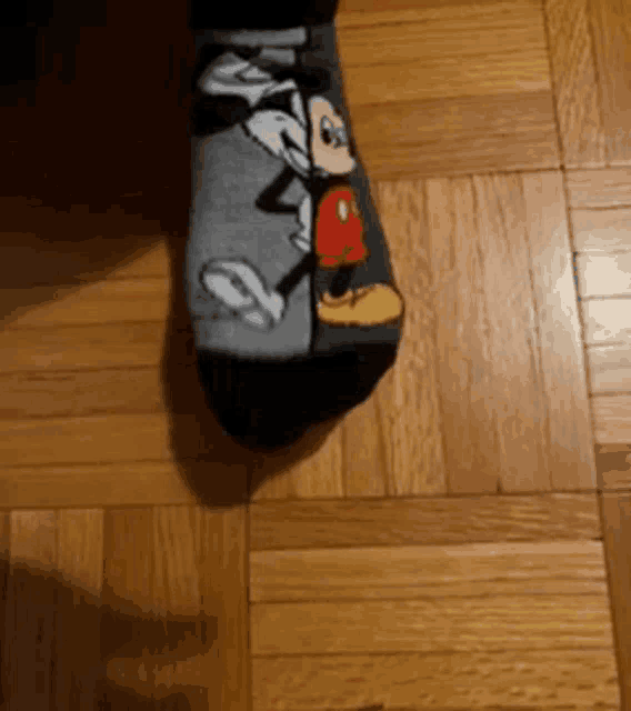 a pair of mickey mouse socks are on a wooden floor