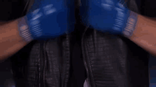 a close up of a person wearing boxing gloves and a black jacket .