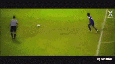 a soccer player in a blue jersey is kicking the ball while a referee watches