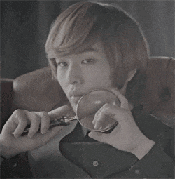 a young man holds a magnifying glass in his mouth