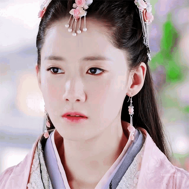a close up of a woman wearing a pink and purple dress and earrings