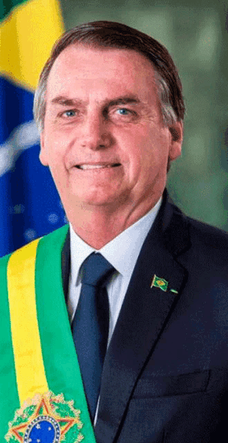 a man in a suit and tie is smiling in front of a brazilian flag .