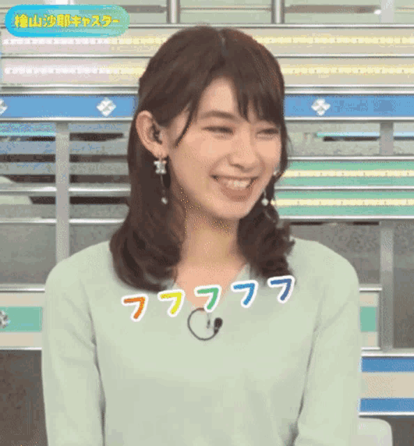a woman wearing a green shirt is smiling with a rainbow of letters around her neck .