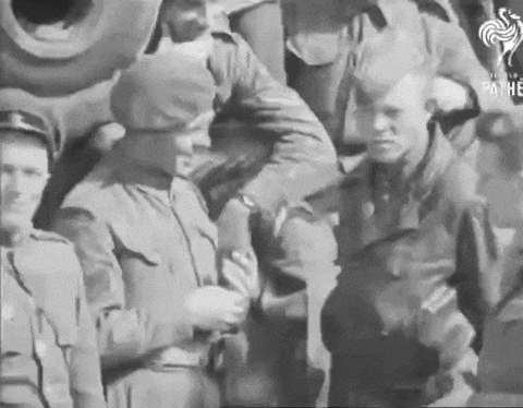 a black and white photo of a group of soldiers standing in front of a tank .