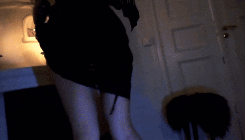 a woman in a black dress is standing in a dark room with a candle