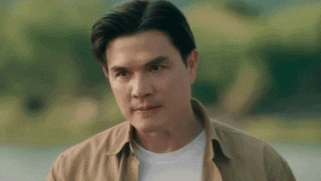 a man in a tan shirt is looking at the camera .