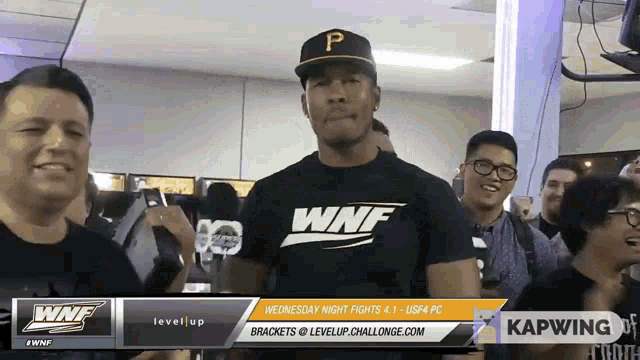 a man wearing a black shirt that says wnf stands in front of a crowd