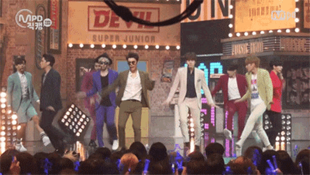 a group of young men are performing on stage in front of a sign that says super junior