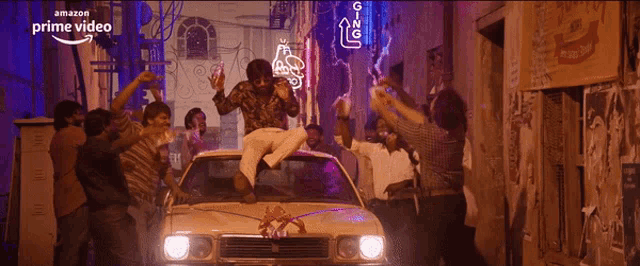 a man is sitting on the roof of a car surrounded by people with the words amazon prime video on the bottom