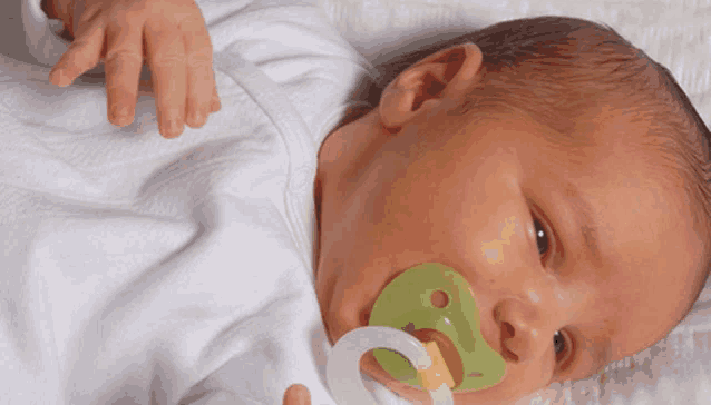 a baby is laying down with a pacifier in its mouth