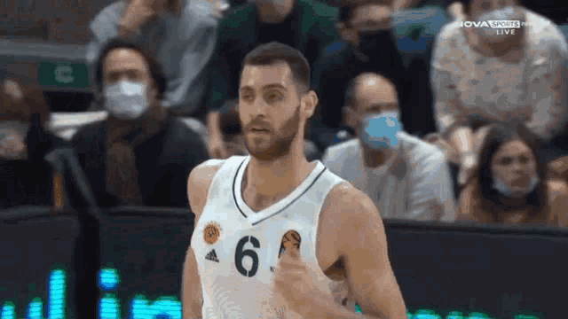 a basketball player wearing a number 6 jersey stands in front of a crowd