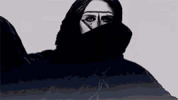 a black and white photo of a woman wearing a black veil over her face .
