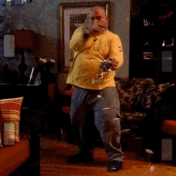 a man in a yellow nike shirt is dancing in a living room .