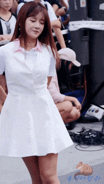 a woman in a white dress is dancing in front of a crowd with chinese writing on the bottom