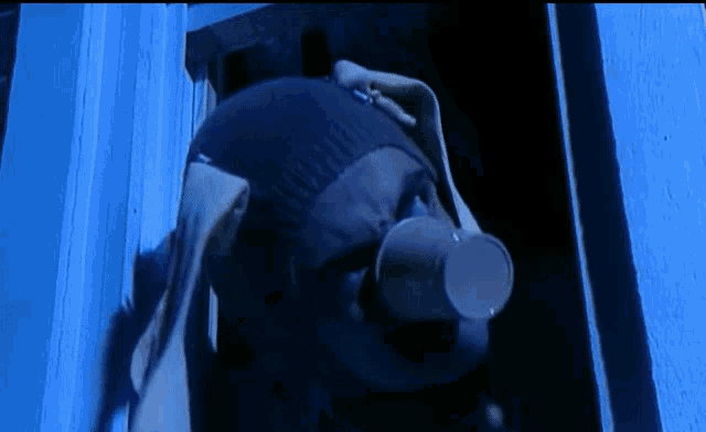 a person with a cup in their mouth standing in a doorway