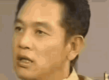 a close up of a man 's face making a funny face and looking at the camera .