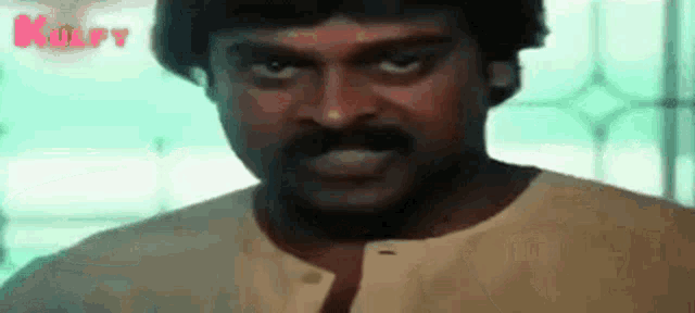 a man with a mustache is making a funny face while wearing a white shirt .