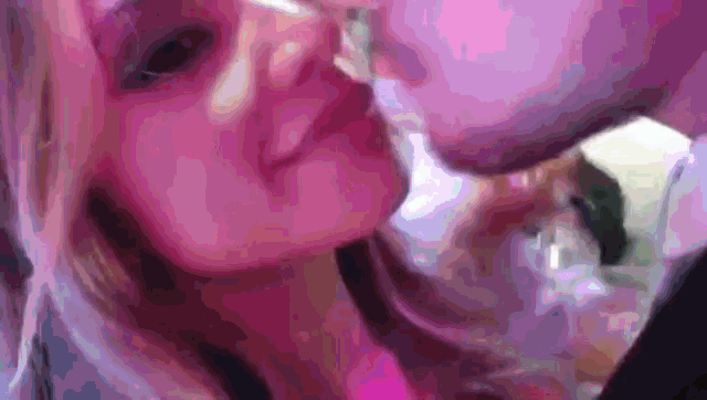 a man and a woman are kissing each other in a purple light .