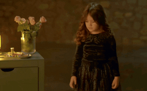 a woman in a white dress sits next to two little girls in black dresses