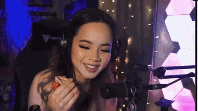 a woman wearing headphones and holding a strawberry in front of a microphone
