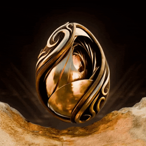 a gold ring with a swirl on it is on a rock