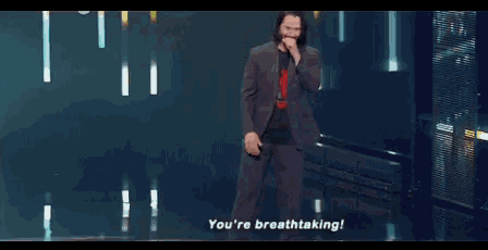 a man in a suit is singing into a microphone and saying you 're breathtaking .