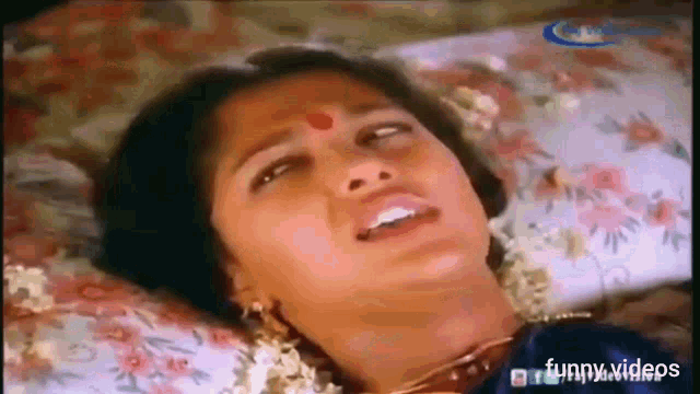 a woman is laying on a bed with her mouth open and a floral pillow .