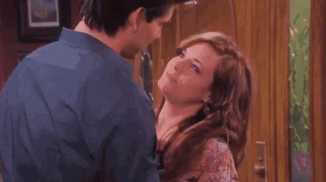 a man and a woman are hugging and kissing in front of a door .