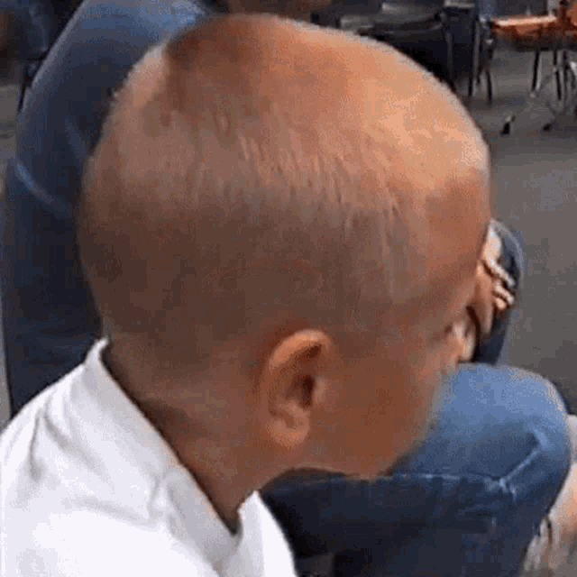 a young boy with a shaved head is sitting next to a woman in a chair .