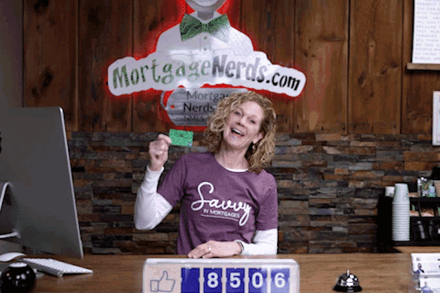 a woman in a purple shirt is standing in front of a sign that says mortgage nerds.com