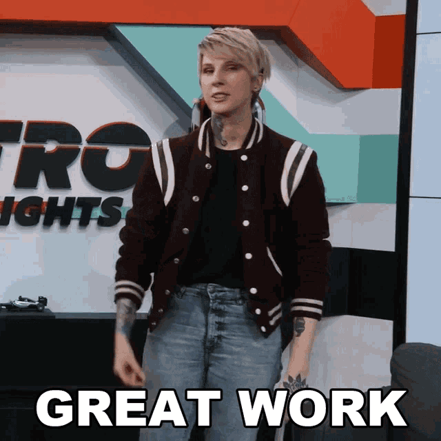 a woman wearing a varsity jacket stands in front of a sign that says great work