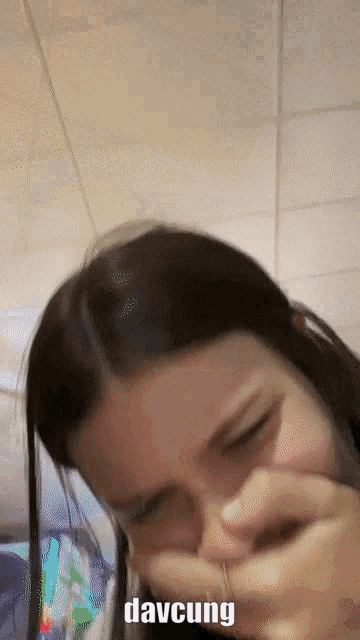 a woman wipes her nose with her hand and the word davcung is on the bottom right