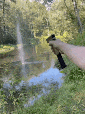 a person is holding a gun near a river