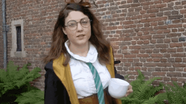 a woman in a harry potter costume is holding a cup of coffee