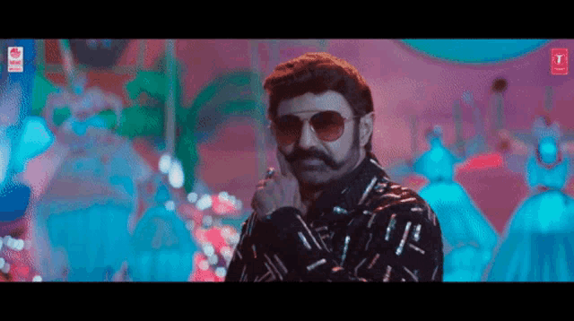a man with a mustache and sunglasses is standing in front of a group of people .