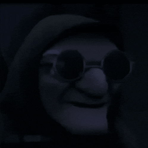 a person wearing a hood and sunglasses is smiling in a dark room .