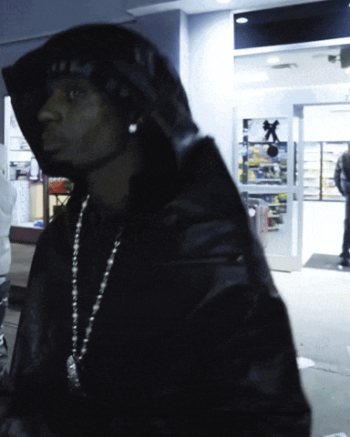 a man in a hooded jacket stands in front of a store door