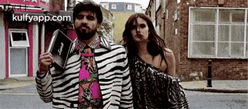 a man and a woman are walking down a street .