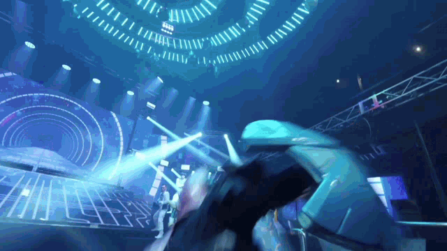 a person in a blue suit is standing in a dark room with a lot of lights