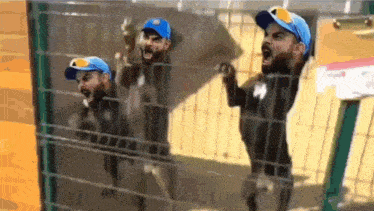 a man in a blue hat is behind a fence with his head visible