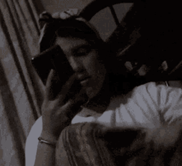 a girl is sitting on a bed holding a cell phone in her hand .