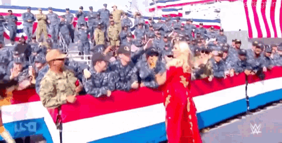 a woman in a red dress stands in front of a crowd of soldiers