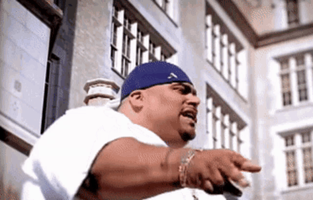 a man wearing a white shirt and a blue hat points at something
