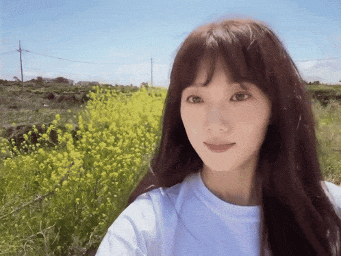 a woman in a white shirt is standing in a field of yellow flowers